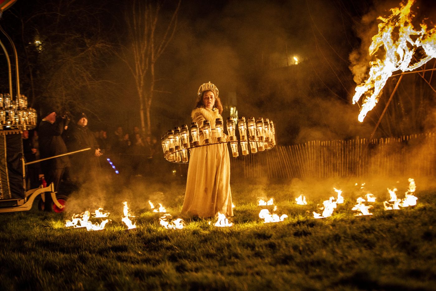 A performer standing in a ring of fire with a great flame burning behind them